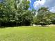 A backyard with green grass, tall trees, and a large rock at 55 Ridge Haven Dr, Louisburg, NC 27549