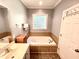 Bathroom features a tiled tub, white cabinets, and a window letting in natural light at 55 Ridge Haven Dr, Louisburg, NC 27549