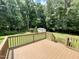 A brown wooden deck with a railing that leads to a yard with green grass, tall trees, and a storage shed at 55 Ridge Haven Dr, Louisburg, NC 27549