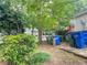 Landscaped backyard with recycling containers, mature trees, and garden, perfect for relaxation and outdoor activities at 5810 Shady Grove Cir, Raleigh, NC 27609