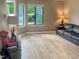 Bright and open living room with large windows, hardwood floors, and a cozy sofa at 5810 Shady Grove Cir, Raleigh, NC 27609