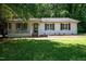 Charming single-story home with white painted brick, green shutters, manicured lawn, and inviting front porch at 6501 Battleford Dr, Raleigh, NC 27613