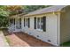 Brick home exterior shows side porch with white rails, trimmed windows with black shutters, and mature landscaping at 6501 Battleford Dr, Raleigh, NC 27613