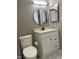 Bathroom with white vanity, round mirror, toilet, and gray walls at 807 W Trinity Ave # 209, Durham, NC 27701