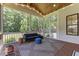 Cozy screened porch with wood ceiling, black sofa, rug and view of wooded back yard at 8420 Bells Lake Rd, Apex, NC 27539