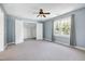 Large carpeted bedroom with blue walls has a ceiling fan, window with backyard view, and walk-in closet at 917 Haddon Hall Dr, Apex, NC 27502
