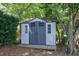 View of the painted shed with traditional double doors and windows, nestled among mature trees at 917 Haddon Hall Dr, Apex, NC 27502