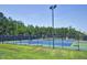 Full tennis court, surrounded by fencing and lush green trees at 917 Haddon Hall Dr, Apex, NC 27502
