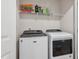 Bright laundry room with white washer, dryer, and convenient overhead shelving for storage at 933 Weatherby Ln, Creedmoor, NC 27522
