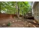 An inviting backyard with a wooden deck and steps leading to a mulched area, surrounded by trees and a wooden fence at 100 Redfoot Run Rd, Chapel Hill, NC 27516