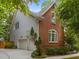 A brick and siding home with a two car garage, surrounded by lush greenery and mature trees on a sunny day at 100 Redfoot Run Rd, Chapel Hill, NC 27516