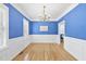 Elegant dining room with blue walls, white wainscoting, hardwood floors, and a chandelier at 107 Roan Dr, Garner, NC 27529