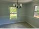 Dining room with gray tile flooring, neutral walls with chair rail, large windows with backyard view and black chandelier at 108 Shadowbrook Dr, Hillsborough, NC 27278