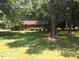 A quaint brick home is surrounded by mature trees and a lush green lawn, creating a serene and inviting atmosphere at 108 Shadowbrook Dr, Hillsborough, NC 27278