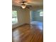 Open living room features hardwood flooring, ceiling fan, large windows overlooking yard and connecting dining room area at 108 Shadowbrook Dr, Hillsborough, NC 27278