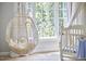 Light-filled Bedroom with a stylish hanging chair and white crib near a large window at 110 Duckwood Ln, Cary, NC 27518
