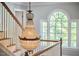 Bright foyer featuring a crystal chandelier, staircase with white banister and a large arched window at 110 Duckwood Ln, Cary, NC 27518
