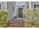 Front door with brick steps, trimmed shrubs, and wall mounted lights at 110 Duckwood Ln, Cary, NC 27518