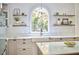 Bright kitchen with island, floating shelves, white countertops, and arched window overlooking the yard at 110 Duckwood Ln, Cary, NC 27518
