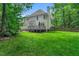 Rear view of the house from the yard with a deck, lawn, and a wooded area at 12 Gatesway Ct, Durham, NC 27707