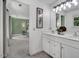 Bright bathroom with double sink vanity, framed mirror, and doorway to an adjacent bedroom at 12 Gatesway Ct, Durham, NC 27707