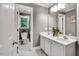 Bathroom with double sink vanity, framed mirror, gray paint, and doorway to an adjacent shower-tub at 12 Gatesway Ct, Durham, NC 27707