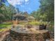 Backyard view showcasing stone firepit sitting area, screened porch and wooded surround at 126 Captains Ct, Durham, NC 27712