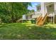 Backyard featuring green grass, mature trees, and a wooden deck with stairs at 144 Greenmont Ln, Cary, NC 27511