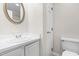 Well-lit bathroom featuring a single sink, a round mirror, and a toilet at 144 Greenmont Ln, Cary, NC 27511