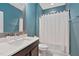 A teal bathroom boasts an undermount sink, vanity and a bathtub with a shower and white curtain at 1523 Anthology Dr, Durham, NC 27703