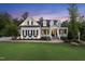 A two-story white farmhouse home with black shutters, covered front porch, and a manicured front lawn at twilight at 175 Stonecrest Way, Pittsboro, NC 27312