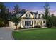 A two-story white farmhouse home with black shutters, covered front porch, and a manicured lawn during twilight at 175 Stonecrest Way, Pittsboro, NC 27312