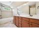 Bright bathroom featuring a double vanity, wood cabinets, and white counters, with tub and tile flooring at 204 Plantation Dr, Youngsville, NC 27596