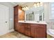 Elegant bathroom featuring double sink vanity, wood cabinets, and granite counters, well lit by sconces and inset lights at 204 Plantation Dr, Youngsville, NC 27596