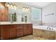 Primary bath boasts double vanity, soaking tub with tile surround, and glass block window at 204 Plantation Dr, Youngsville, NC 27596