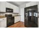 Modern kitchen featuring black appliances, white cabinets, and hardwood flooring, perfect for culinary enthusiasts at 2069 White Pond Ct, Apex, NC 27523