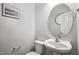 Elegant powder room featuring pedestal sink, round mirror, and beach-themed wall art at 2069 White Pond Ct, Apex, NC 27523
