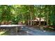 Charming log cabin nestled among mature trees with a gravel driveway and multiple outbuildings at 3263 S Jim Minor Rd Rd, Haw River, NC 27258