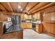 Cabin kitchen features wood cabinets, stainless steel appliances, stone tile floors, and wood walls and ceilings at 3263 S Jim Minor Rd Rd, Haw River, NC 27258