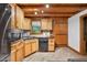 Cabin kitchen featuring wood cabinets, a black counter, stainless steel appliances, and wood-paneled walls at 3263 S Jim Minor Rd Rd, Haw River, NC 27258