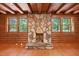 A cozy living room showcasing a stone fireplace, wood walls, wood trim windows and exposed wood ceiling beams at 3263 S Jim Minor Rd Rd, Haw River, NC 27258
