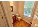 Bathroom with wood-look flooring, updated sink and vanity, toilet, window with blinds, and a wall-mounted mirror at 332 Bridgegate Dr, Cary, NC 27519