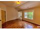 Bright bedroom with wood flooring, baseboard trim, large window, and door to another room with natural light at 332 Bridgegate Dr, Cary, NC 27519