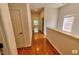 Long wood-floored hallway with white walls, doors, trim, and a window at the end looking outside at 332 Bridgegate Dr, Cary, NC 27519