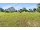 Spacious backyard with lush lawn, mature trees, garden beds, and a glimpse of the home's exterior at 3831 Abattoir Rd, Angier, NC 27501