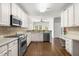 Charming kitchen features stainless appliances, white cabinetry, built in desk, and wood flooring at 410 Willingham Rd, Morrisville, NC 27560