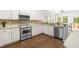 Charming kitchen features stainless appliances, white cabinetry, wood flooring and bright natural light at 410 Willingham Rd, Morrisville, NC 27560