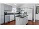Bright kitchen featuring gray cabinets, stainless steel appliances, island and hardwood floors at 4505 Woodlawn Dr, Raleigh, NC 27616