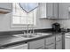 This kitchen area features a stainless steel sink with gray cabinets, hardwood floors and natural light at 4505 Woodlawn Dr, Raleigh, NC 27616