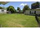 View of a large, grassy backyard with a metal fence, storage shed, and mature trees at 521 S Lombard St, Clayton, NC 27520
